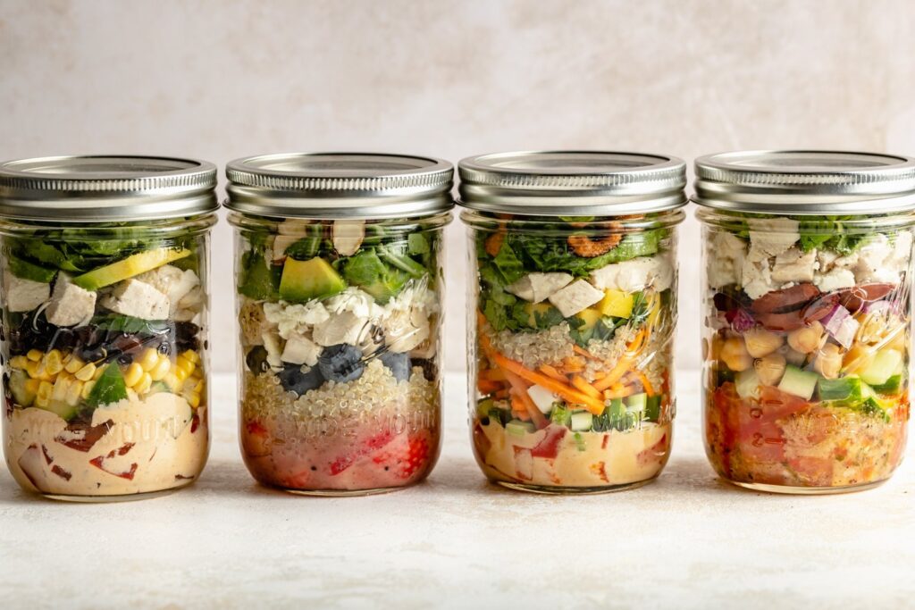 High-protein healthy lunch idea with layered mason jar salad of spinach, chicken, and strawberries.